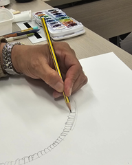 hand holding a pencil and drawing during an art therapy class
