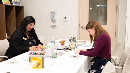 two people seated creating art through art therapy