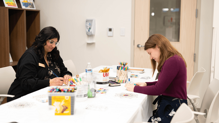 two people seated creating art through art therapy