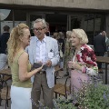 Three people enjoying conversation in the garden with others mingling in the background