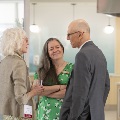 Three people conversing with kitchen in background