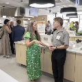 Two people mingling in a kitchen with others in the background