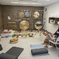 A seated woman poses with sound immersion instruments