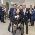 Three men pose for a picture with others in the background