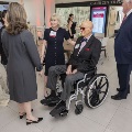 A seated man in sunglasses being greeted by event attendees