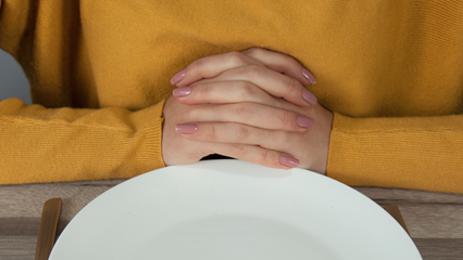 Hands folder in front of plate for mindful eating