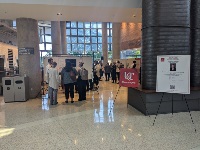 Two tripod stands in front of a group of people discussing. One stand has a poster of the University of Cincinnati Department of Neurosurgery logo and the other has a poster of a flyer for a presentation.