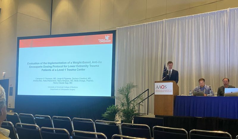 Image of Cameron Thomson MD, 2021-2022Jorge Figueras BS, 2021-2022 Orthopaedic Research Fellow presenting podium and poster at AAOS 2022 in Chicago